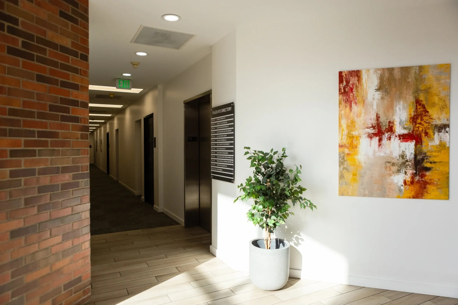 A plant in a white pot on the floor of an office building.