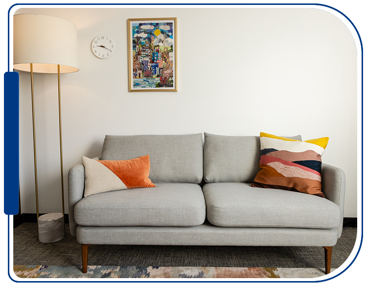 A couch with pillows and a lamp in the background.